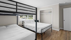 A bunk bed room with a window, a closet, and a door. - Newly Renovated Unit in Central Spfld! #204 (Springfield)