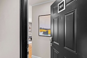 A hallway with a black door marked '201' and a framed abstract painting on the wall.