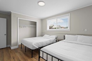 A bedroom with two beds, a closet, and a window with blinds. - Newly Renovated Unit in Central Spfld! #101 (Springfield)