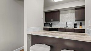 A modern kitchen with dark cabinets, a microwave, a coffee maker, and a marble countertop. - Newly Renovated Unit in Central Spfld! #203 (Springfield)