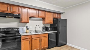 A kitchen with wooden cabinets, a black stove, a black refrigerator, a microwave, and a dishwasher.