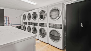 A laundry room with multiple washing machines, a marble countertop, and a black cabinet. - Newly Renovated Unit in Central Spfld! #304 (Springfield)