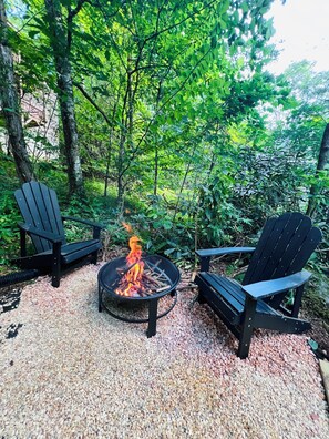 Feuerstelle mit zwei Adirondack-Stühlen in einem Garten.