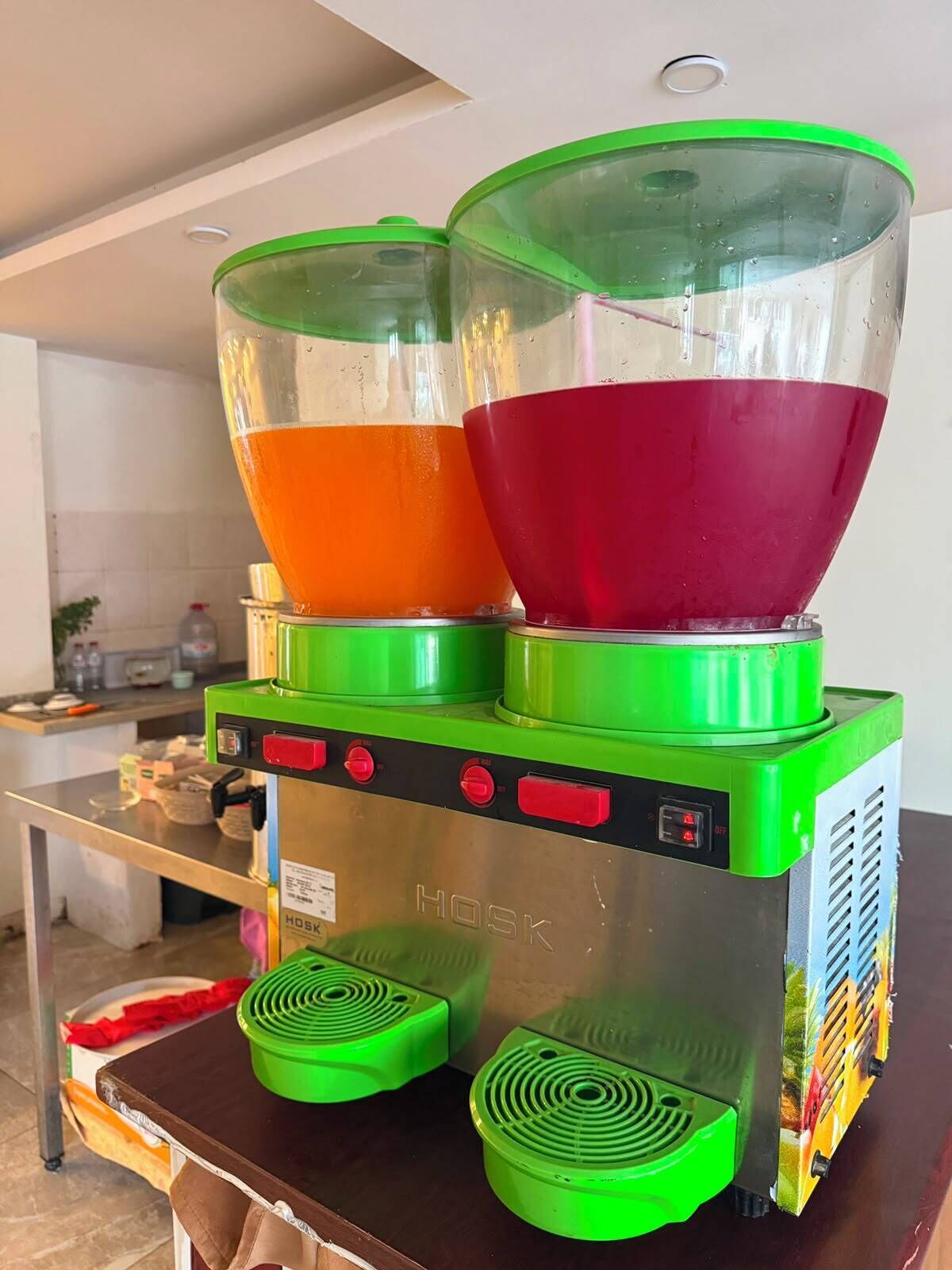 A commercial kitchen with a green and silver food processor, two large mixing bowls, and a stainless steel table.
