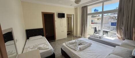Une chambre d’hôtel avec deux lits, une télévision, un balcon avec vue sur la ville et un ventilateur de plafond.