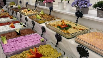 Un bufé con diversas opciones de comida, cada una identificada con una etiqueta.