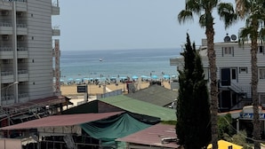 A coastal hotel with a view of the beach, multiple balconies, and a sign indicating a photo studio. - Holiday Hotel (Erdemli)
