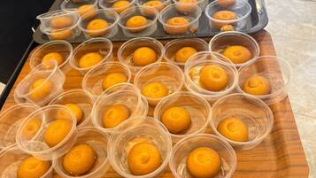 A tray with multiple plastic containers holding round, golden-brown baked goods, likely muffins or cakes, on a wooden surface.