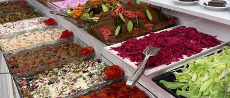 Un bufé con diversas opciones de comida, incluyendo ensaladas, vegetales y postres.