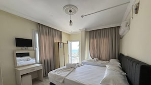 A hotel room with a bed, a desk, a television, and a view of the sea. - Holiday Hotel (Erdemli)