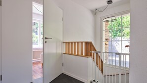 A staircase with a wooden handrail, a white door, and a view of the outside. - Nature & tranquillity I Bern I Family I Parking free I Pet-friendly (Köniz)