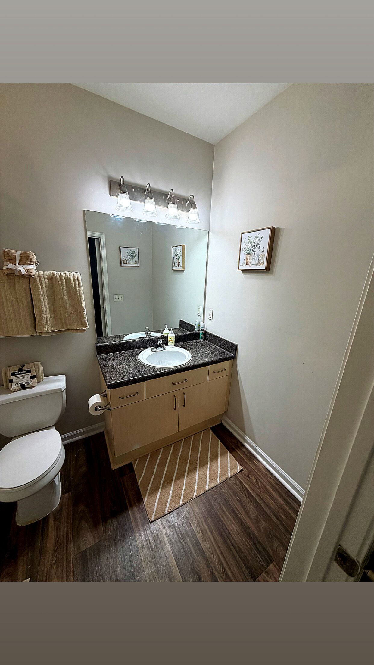 Un baño con inodoro blanco, lavamanos con espejo y zona de ducha.