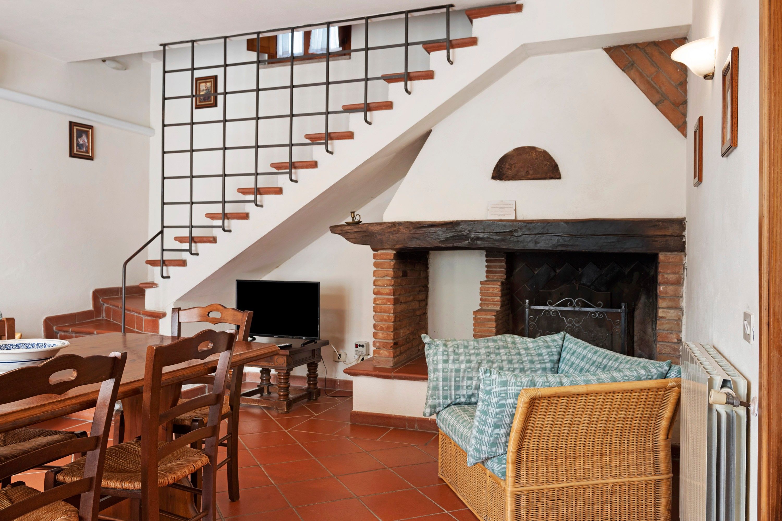 Un comedor con mesa y sillas de madera, televisor y chimenea con un plaid escocés.