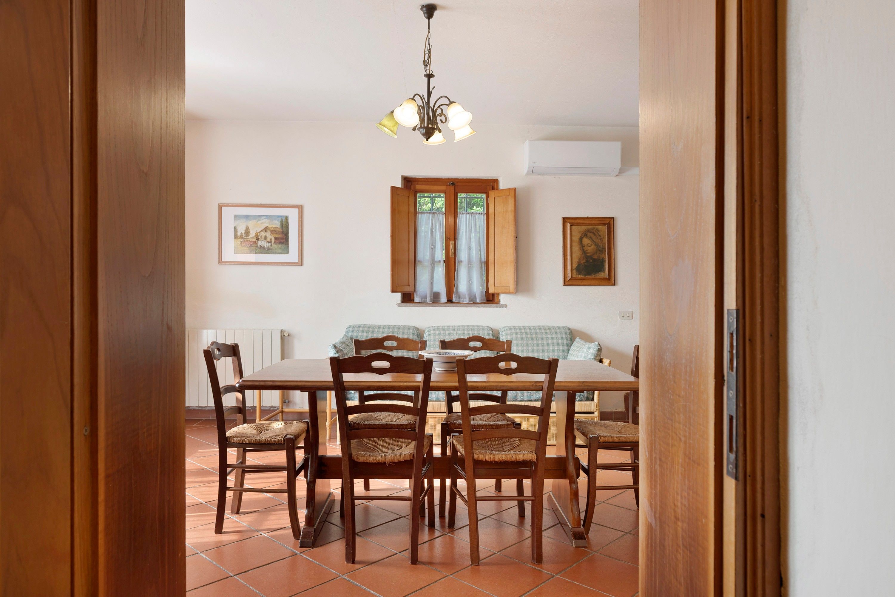 A dining area with a wooden table, chairs, and a chandelier.