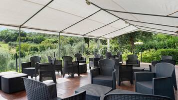 An outdoor seating area with a canopy, wicker furniture, and a view of greenery.