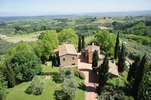 Une propriété rurale avec des bâtiments en pierre, un jardin et une vue sur des collines ondulantes.