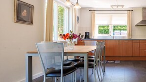 A dining area with a table, chairs, and a vase of flowers. - Comfortable country house in Drenthe (Schoonloo)