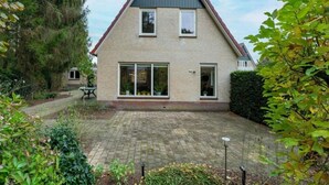 A two-story house with a brick facade, large windows, and a paved backyard. - Comfortable country house in Drenthe (Schoonloo)