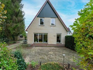Ein zweigeschossiges Haus mit Ziegelaußenwand, großen Fenstern und einem gepflasterten Hinterhof.
