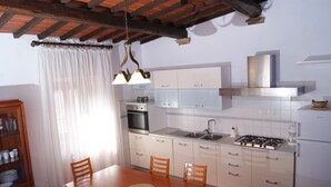 Una cocina con mesa, sillas, estufa, horno y armarios.