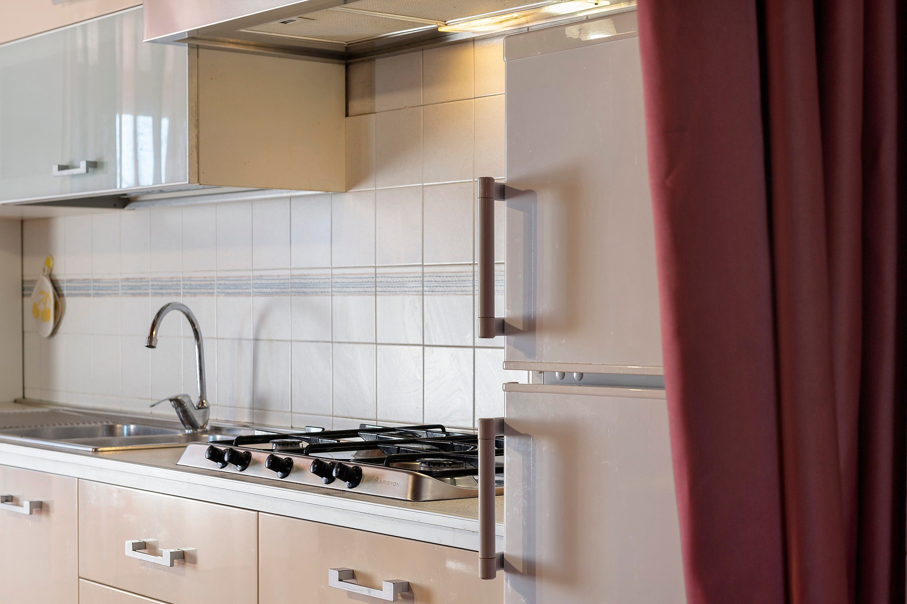 A kitchen with a gas stove, stainless steel cabinets, and a tiled backsplash.
