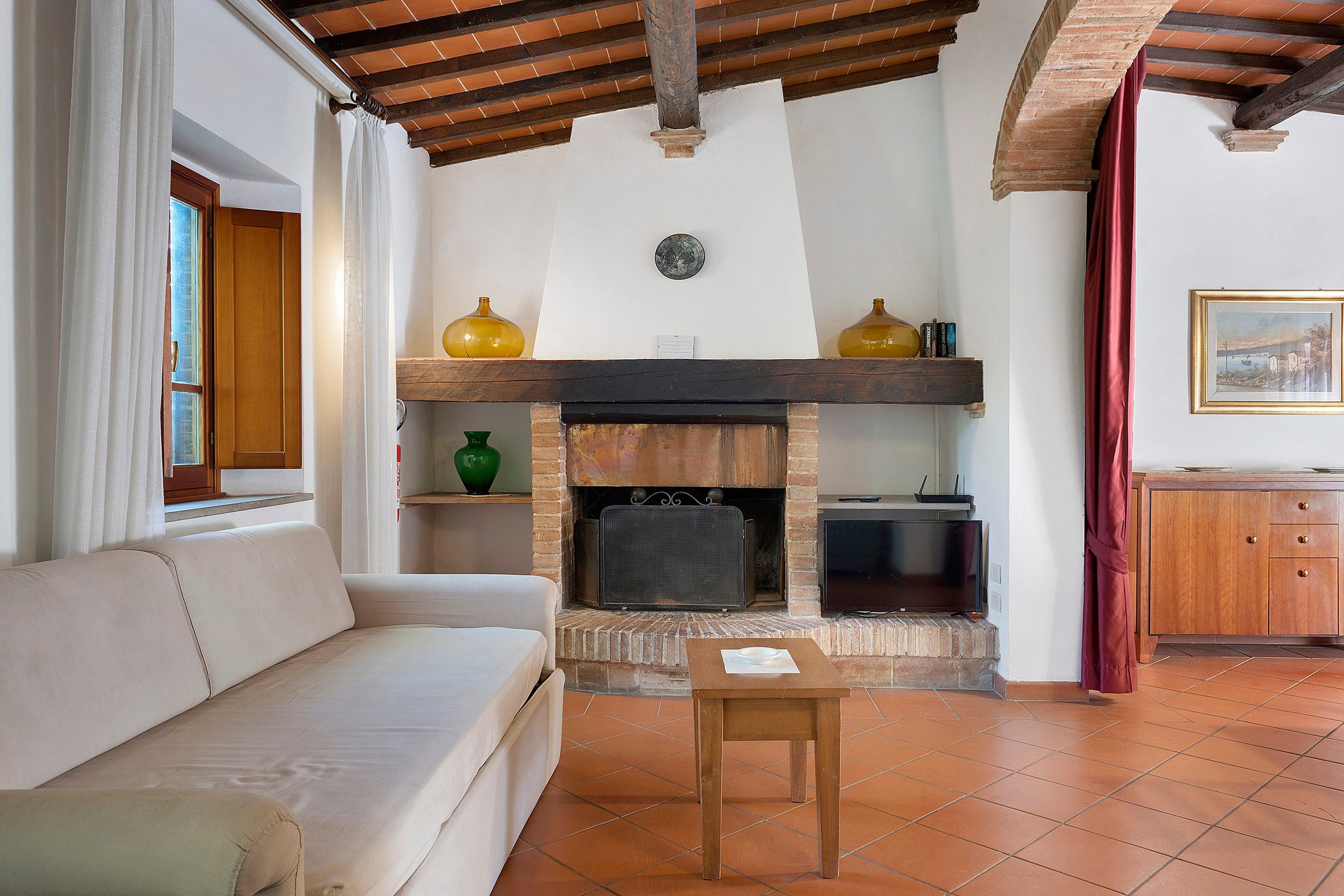 A living room with a fireplace, a sofa, a table, and a television.