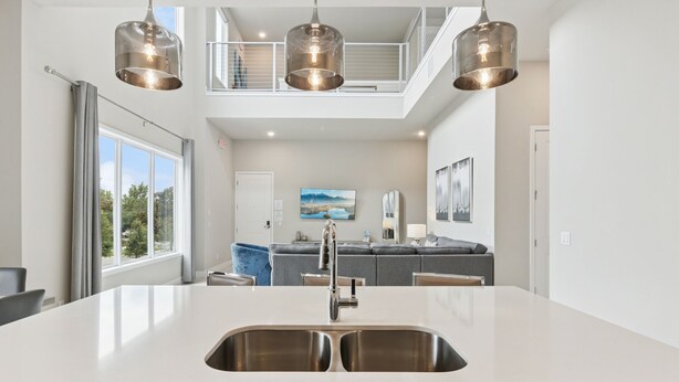 A modern kitchen with a large island, stainless steel sink, and pendant lighting. - Skyline Luxe Retreat  Loft, Pool Table & Rooftop Balcony Near Disney (Kissimmee)