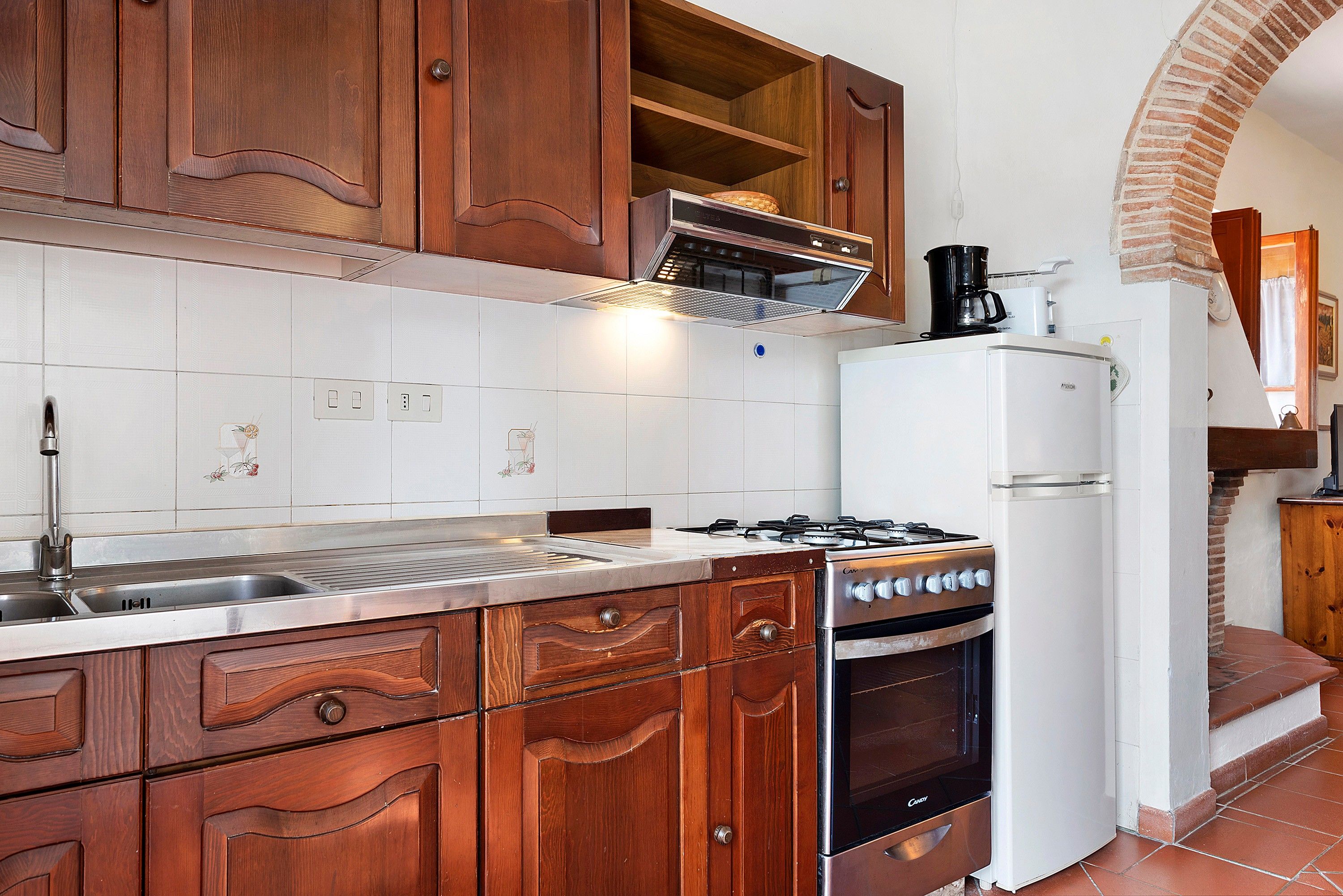 A kitchen with wooden cabinets, a gas stove, a built-in oven, a microwave, and a refrigerator.