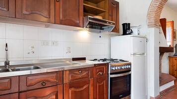 A kitchen with wooden cabinets, a gas stove, a built-in oven, a microwave, and a refrigerator.