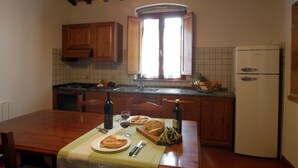 Una cocina con armarios de madera, salpicadero azulejado, una ventana y un refrigerador.