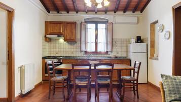 Una cocina con una mesa de comedor, sillas, estufa y refrigerador.