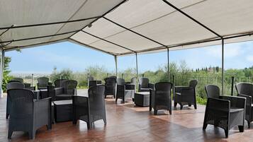 Een terras buiten met rieten meubels en een overdekt gedeelte.