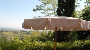 Un espacio para comer al aire libre con una mesa, sillas y una sombrilla.