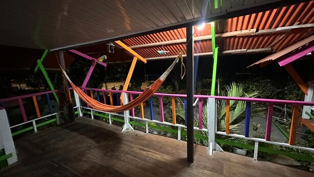 Una hamaca bajo una pérgola de madera con barandillas de colores.