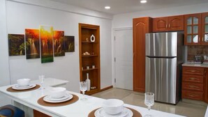 Eine moderne Küche mit einem Edelstahl-Kühlschrank, Holzschränken und einem Essbereich mit einem weißen Tisch für vier Personen.