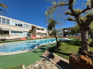 Ein Hotel mit Schwimmbad, einem großen Baum und einem gepflegten Rasen.