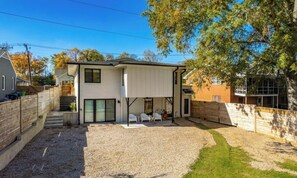Ein modernes, zweistöckiges Haus mit überdachter Terrasse, Kiesauffahrt und einem kleinen Garten.