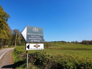 Schild für das Restaurant und die Bar des Buchanan Castle Golf Course, mit einem Pfeil, der den Weg weist.