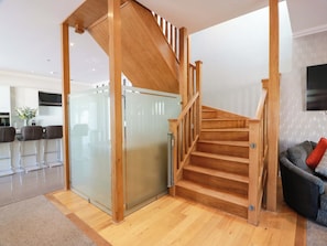 Ein modernes Interieur mit einer Holztreppe, einer Küchenzeile und einer Sitzecke mit einer Couch.