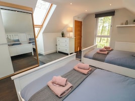 A bedroom with two beds, a dresser, a mirror, and a window with a view.