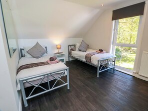Ein Schlafzimmer mit zwei Betten, einem Nachttisch mit Lampe und einem großen Fenster.