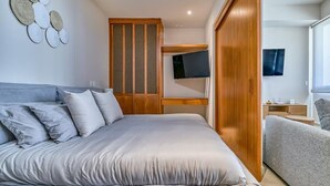 Un dormitorio moderno con una cama grande, un armario de madera y un televisor montado en la pared.