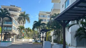 Un patio empedrado con bancos, palmeras y edificios modernos al fondo.
