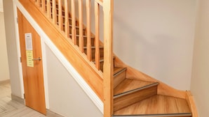 A wooden staircase with a handrail, a door with a notice, and a light-colored floor. - Ledrishmore View (Alexandria)