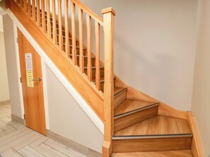 A wooden staircase with a handrail, a door with a notice, and a light-colored floor. - Ledrishmore View (Alexandria)