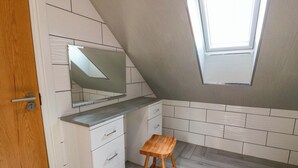 A small, modern kitchen with white cabinetry, a wooden stool, and a skylight. - Ledrishmore View (Alexandria)