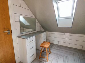 A small, modern kitchen with white cabinetry, a wooden stool, and a skylight. - Ledrishmore View (Alexandria)
