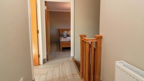 A narrow hallway with a wooden floor, a radiator, and a bed in the background. - Ledrishmore View (Alexandria)