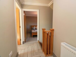 A narrow hallway with a wooden floor, a radiator, and a bed in the background. - Ledrishmore View (Alexandria)
