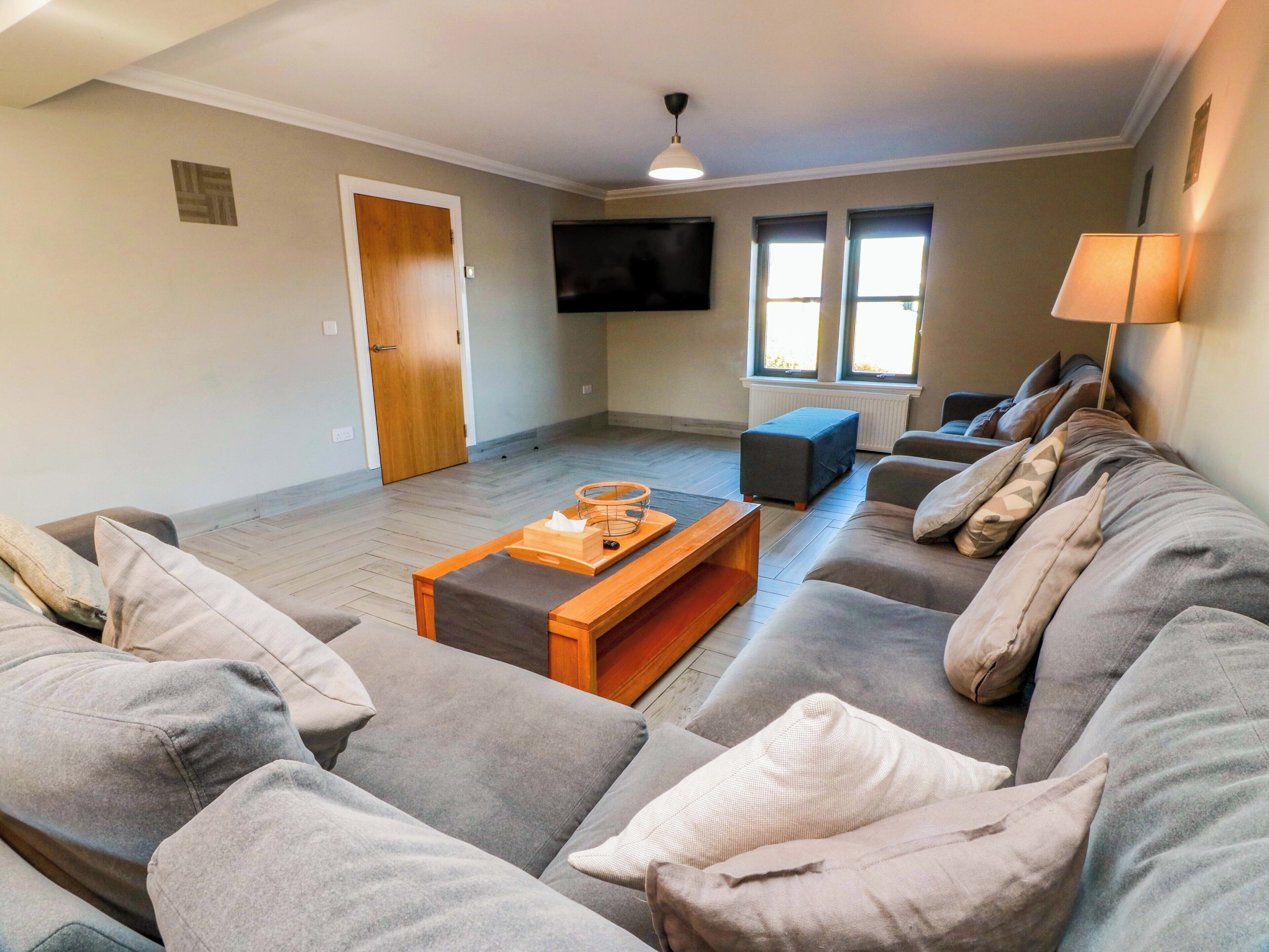 A living room with a sofa set, a coffee table, a TV, and a door.